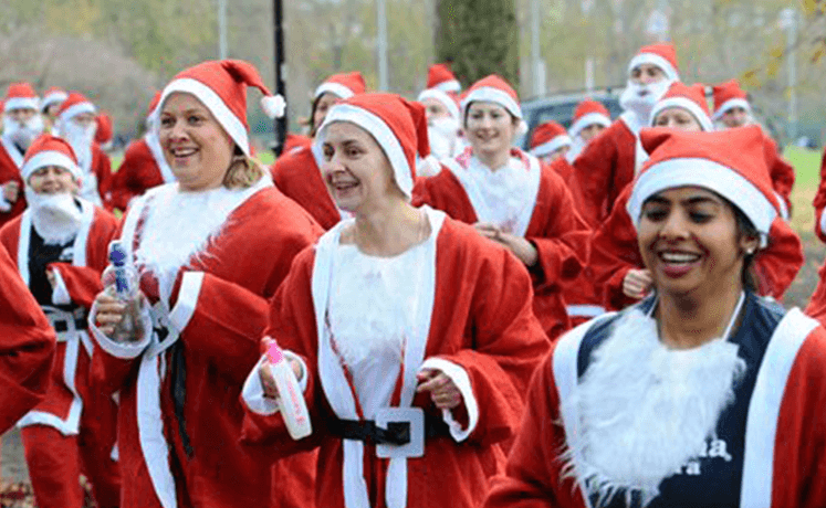 Group of people dressed as Santa running outdoors, spreading holiday cheer.