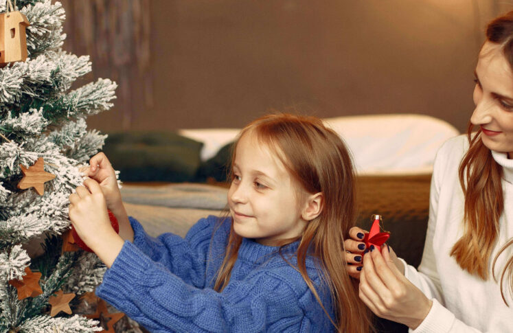 girl and parent decorating Christmas tree